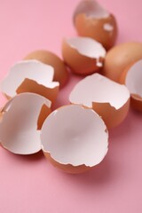 Wall Mural - Pieces of broken eggshells on pink background, closeup