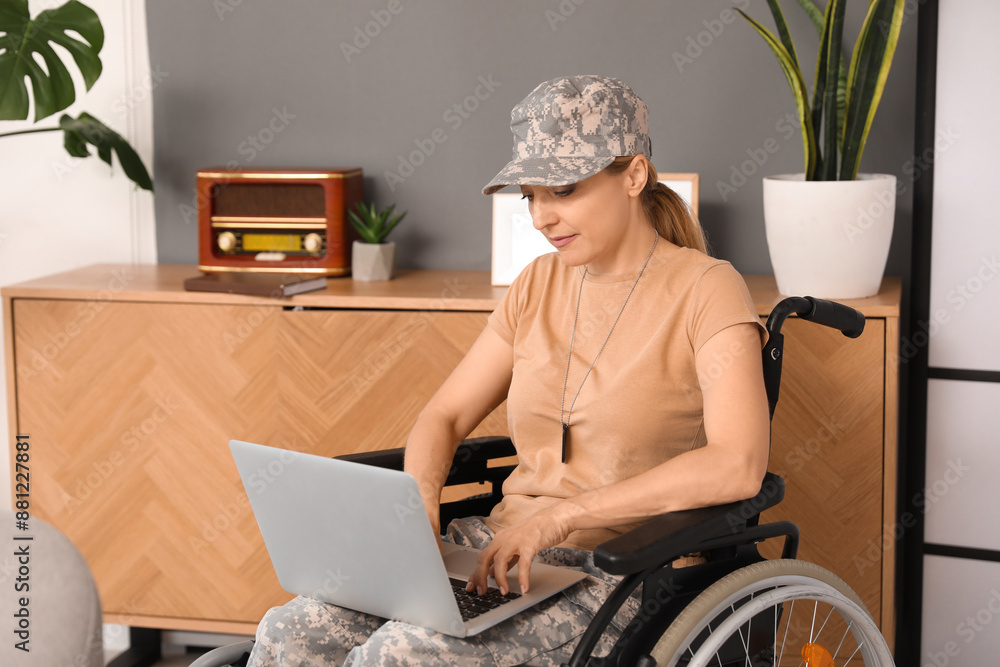 Female soldier in wheelchair using laptop at home