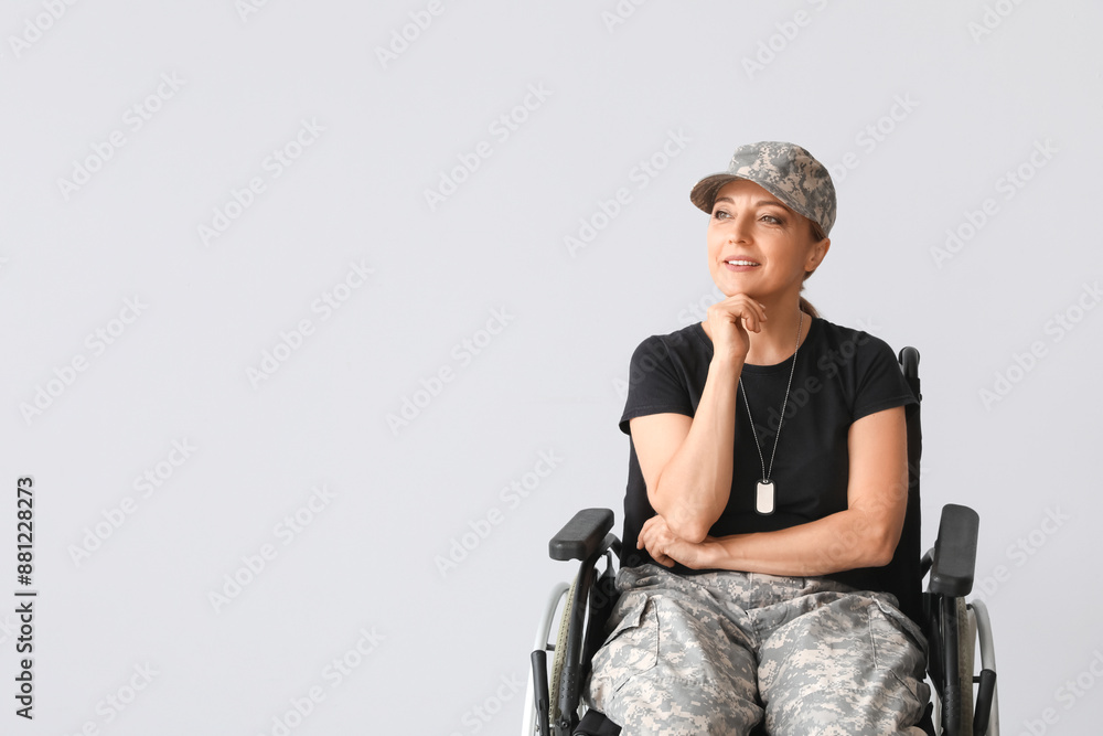 Thoughtful female soldier in wheelchair on light background