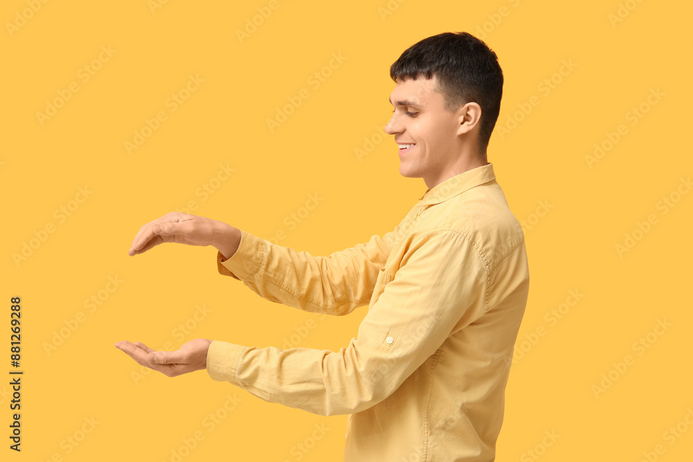 Young deaf mute man using sign language on yellow background