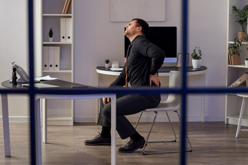 Canvas Print - Young businessman suffering from back pain at table in office