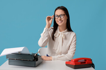 Sticker - Young secretary sitting at table with typewriter on blue background