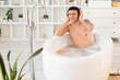 © Pixel-Shot - Young man with headphones taking bath in room