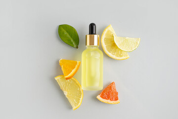 Wall Mural - Composition with bottle of essential oil and fresh citrus fruits on grey background