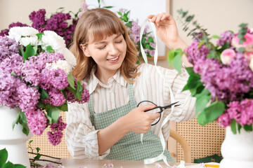 Wall Mural - Female florist cutting ribbon for bouquet with lilacs in flower shop