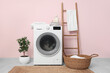 © Pixel-Shot - Modern washing machine with laundry, basket and houseplant near pink wall