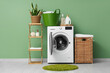 © Pixel-Shot - Modern washing machine with rack, baskets and detergents near green wall
