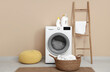 © Pixel-Shot - Modern washing machine with ladder, basket and pouf near beige wall