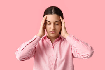 Canvas Print - Beautiful young woman suffering from headache on pink background