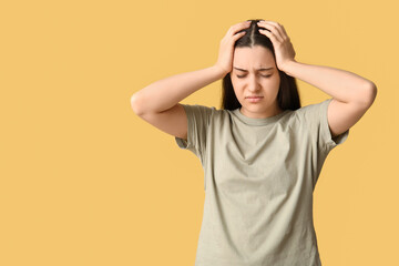 Poster - Beautiful young woman suffering from headache on yellow background