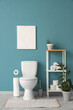 © Pixel-Shot - Interior of restroom with toilet bowl, shelving unit and plants near blue wall