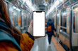 © Peeradontax - A close-up shot of a hand holding a smartphone with a blank screen inside an orange subway train.