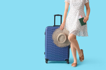 Poster - Young woman with suitcase, straw hat, passport and ticket on blue background