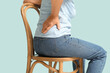 © Pixel-Shot - Mature woman suffering from back pain while sitting on chair on blue background