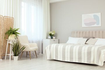 Poster - Large bed, chest of drawers, armchair, houseplants and window with curtains in bedroom. Interior design