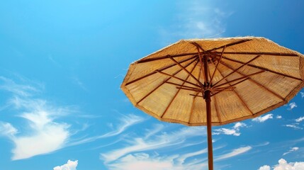 Canvas Print - Summer background Wicker beach umbrella under blue sky