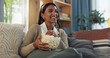 © WesSide/peopleimages.com - Smile, girl and relax on sofa with popcorn for watching movies, streaming comedy film and unwind on weekend for break. Woman, laughing and snack in home for online subscription and entertainment.