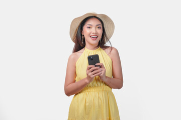 Wall Mural - Young Asian woman in a yellow dress is holding a cell phone smiling to the camera.