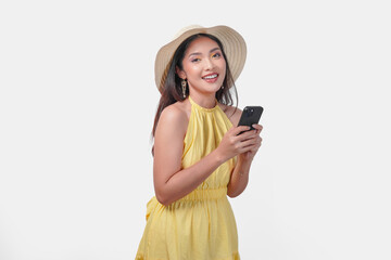 Wall Mural - Young Asian woman in a yellow dress is holding a cell phone smiling to the camera.