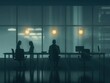 © Khuefa - Silhouetted office employees working late at night, illuminated by dim lights through large windows, creating a moody atmosphere.