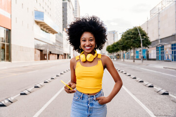 Wall Mural - Beautiful young black woman outdoors in the city - African american female teenager with afro hairstyle portrait 