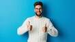 © Nataliia_Trushchenko - A man with glasses is smiling and giving thumbs up. He is wearing a white sweater and standing in front of a blue wall