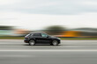 © Armands photography - A black car is driving down the street at high speed with a blurred background. Concept of speeding, disobeying traffic rules, dangerous driving
