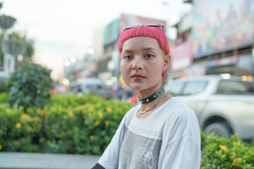 Wall Mural - Portrait of young female Gen z girl pink leather fashion with punk Asian woman sitting at local city park Equality diversity concept