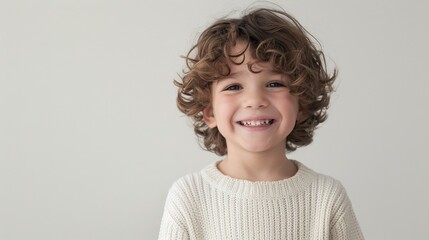 Wall Mural - A young boy with curly brown hair and bright green eyes smiles radiantly at the camera