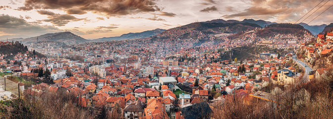 Wall Mural - panorama of Sarajevo as the sun sets behind its rolling hills, casting a colorful hue over the cityscape.