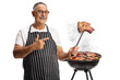 © Ljupco Smokovski - Mature man grilling meat on a barbecue and holding a steak on a fork