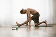 © LIGHTFIELD STUDIOS - A handsome man practices a yoga pose on a mat at home in the morning.