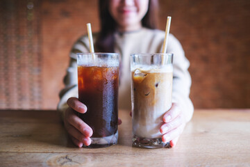 Wall Mural - Closeup image of a young woman holding and serving two glasses of iced coffee