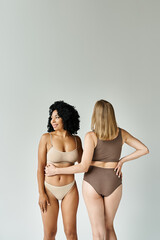 Wall Mural - Two beautiful women in cozy pastel underwear standing next to each other.