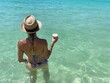 © Nati - back view of the woman whit a hat in the sea having a natural drink