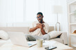 © SHOTPRIME STUDIO - Smiling African American Freelancer Working on Laptop in Modern Home Office Young black guy, a millennial freelancer, is sitting on a comfortable sofa in his modern apartment With a laptop on his lap,