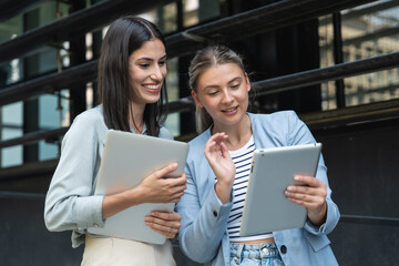 two business women out of office building with laptop and digital tablet. technology used in modern 