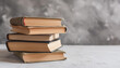 © hardvicore - Pile of old books. World Book Day. Education concept, knowledge and learning. Gray textured backdrop