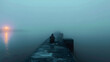 © Arma - A person sitting alone on a pier in the middle of fog, perfect for meditative or reflective compositions, conveys solitude and tranquility with ample copy space.
