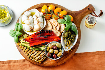 Wall Mural - Board with ITALIAN summer foods and grilled vegetables: mozzarella braid, cherry tomatoes, grilled eggplant and zucchini, olives and capers