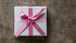 © tonstock - A beautifully wrapped gift box with a pink ribbon on a rustic wooden background, perfect for celebrations and special occasions.