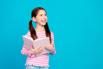 Sticker - Photo of adorable girl with tails dressed striped shirt holding book in hands look at sale empty space isolated on blue color background