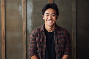 Poster - Portrait of a smiling asian man in his 20s wearing a comfy flannel shirt in front of empty modern loft background