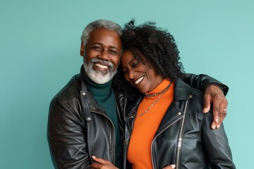 Poster - Portrait of a joyful multicultural couple in their 60s sporting a classic leather jacket on soft teal background