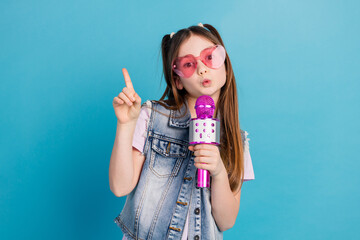 Sticker - Photo portrait of adorable small girl sing karaoke point up empty space dressed stylish denim garment isolated on blue color background