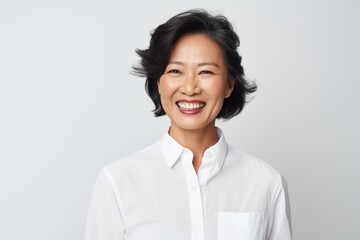 Sticker - Portrait of a grinning asian woman in her 50s wearing a simple cotton shirt in front of plain white digital canvas