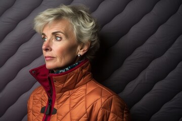 Wall Mural - Portrait of a jovial woman in her 50s sporting a quilted insulated jacket in front of plain cyclorama studio wall