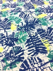 Poster - A close up view of a white fabric with a blue, green, and yellow tropical leaf print