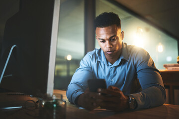 Canvas Print - Night, search and black man at computer with phone, connection and business website at tech startup. Dark, office and businessman at desk with smartphone, networking and typing at digital agency.