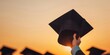 © Tanakorn - A graduate throws their cap in the air at sunset.